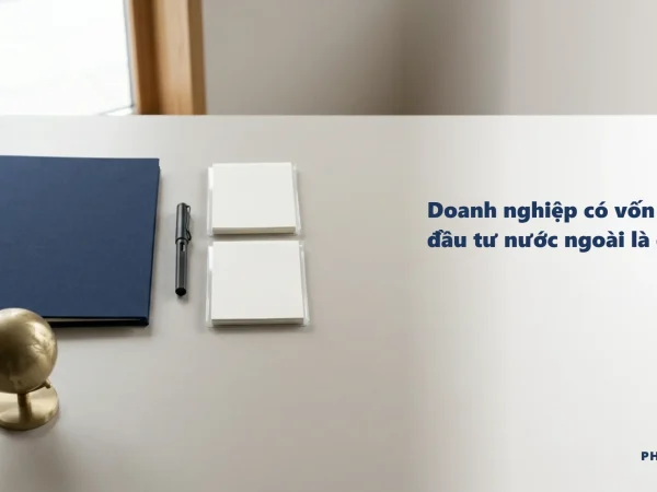 Doanh nghiệp có vốn đầu tư nước ngoài là gì: bìa hồ sơ navy, quả địa cầu đồng, bút và hai tệp tài liệu trên bàn làm việc