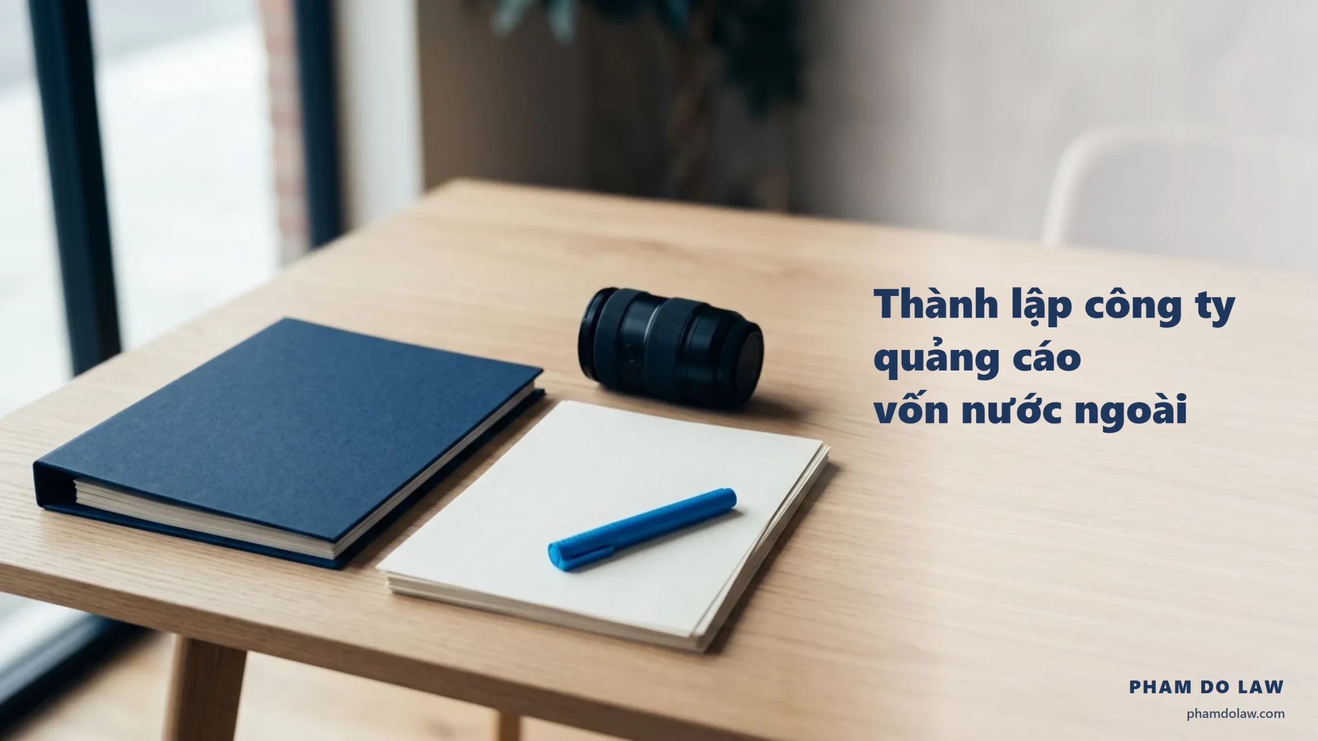 Thành lập công ty quảng cáo vốn nước ngoài: bìa hồ sơ navy, ống kính máy ảnh và bút xanh trên bàn