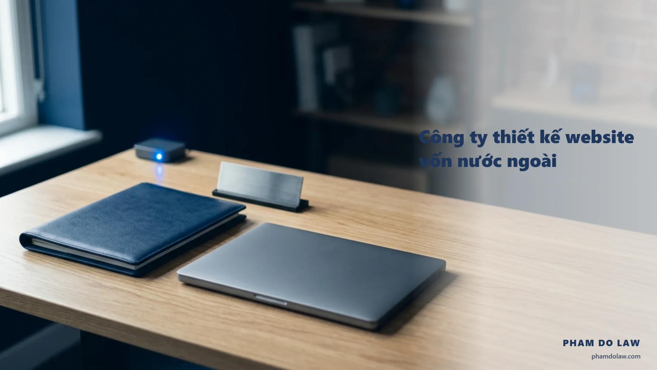 Công ty thiết kế website vốn nước ngoài: bìa hồ sơ navy, máy tính xách tay đóng và biển tên thép trên bàn làm việc