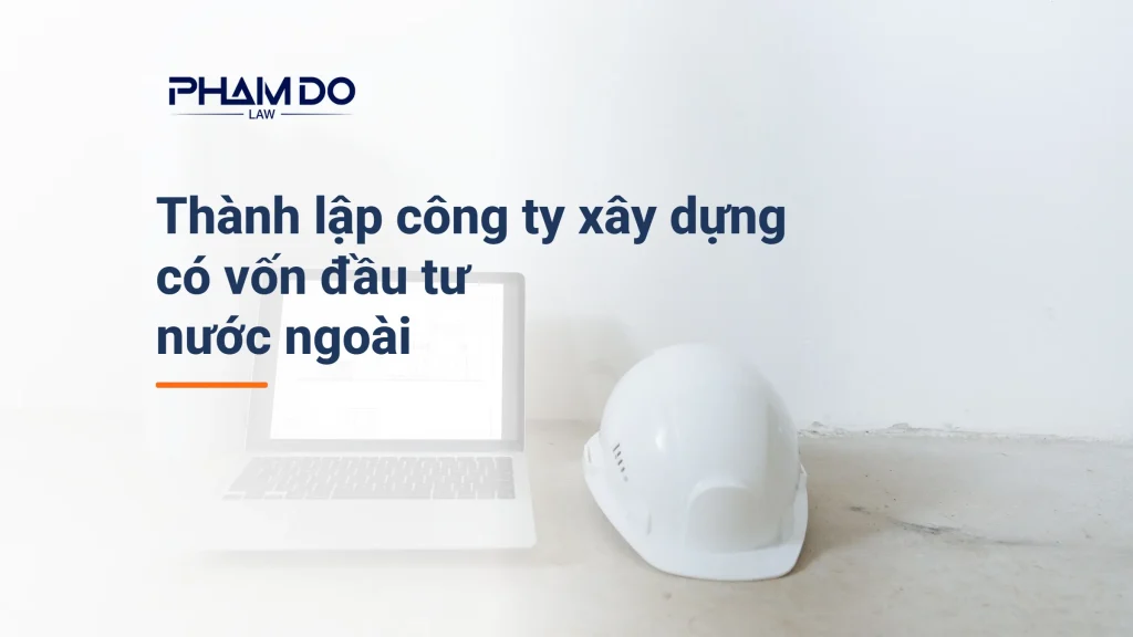 Mũ bảo hộ trắng và máy tính có bản vẽ đặt trên sàn bê tông, minh họa thủ tục thành lập công ty xây dựng có vốn đầu tư nước ngoài